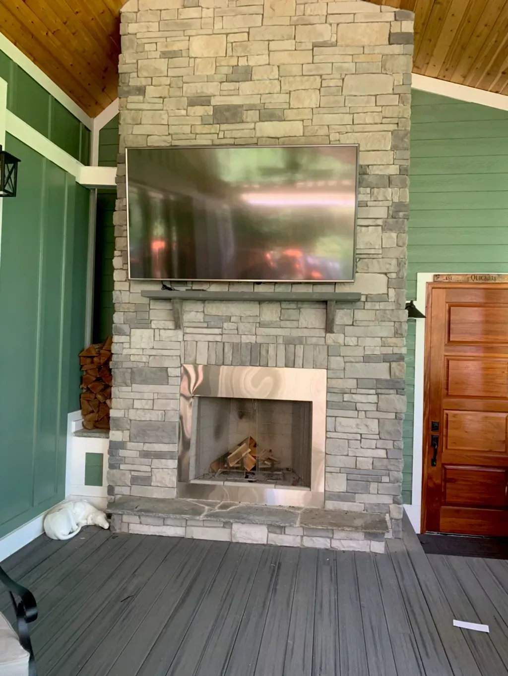 A large stone fireplace with a flat screen tv mounted above it.