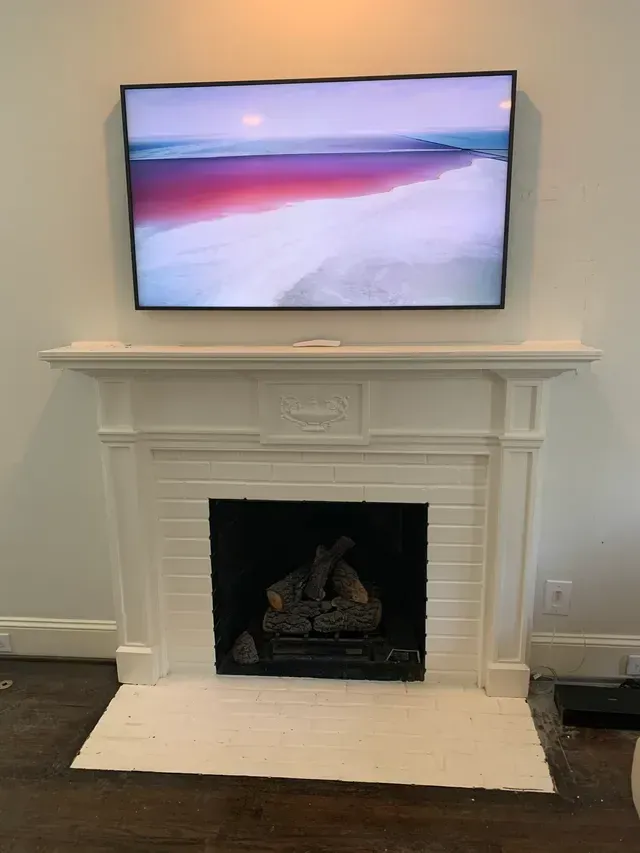 A fireplace with a flat screen tv mounted above it.