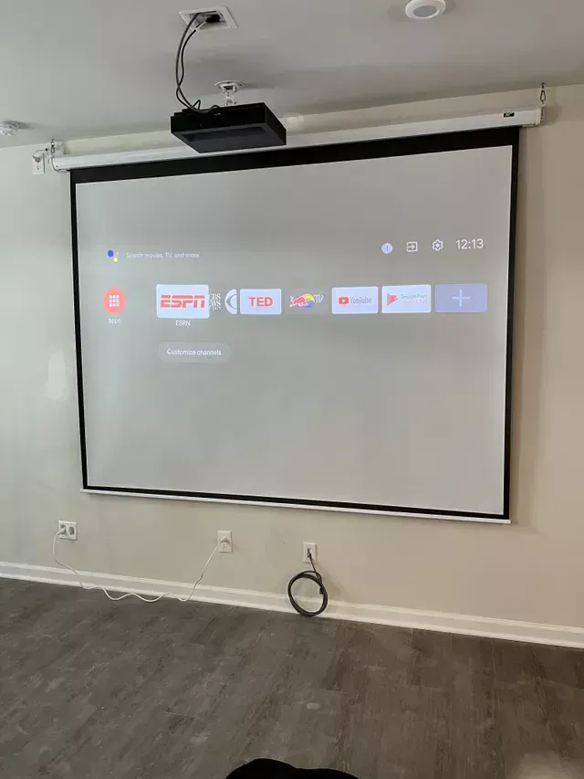 A projector screen is hanging on a wall in a room.