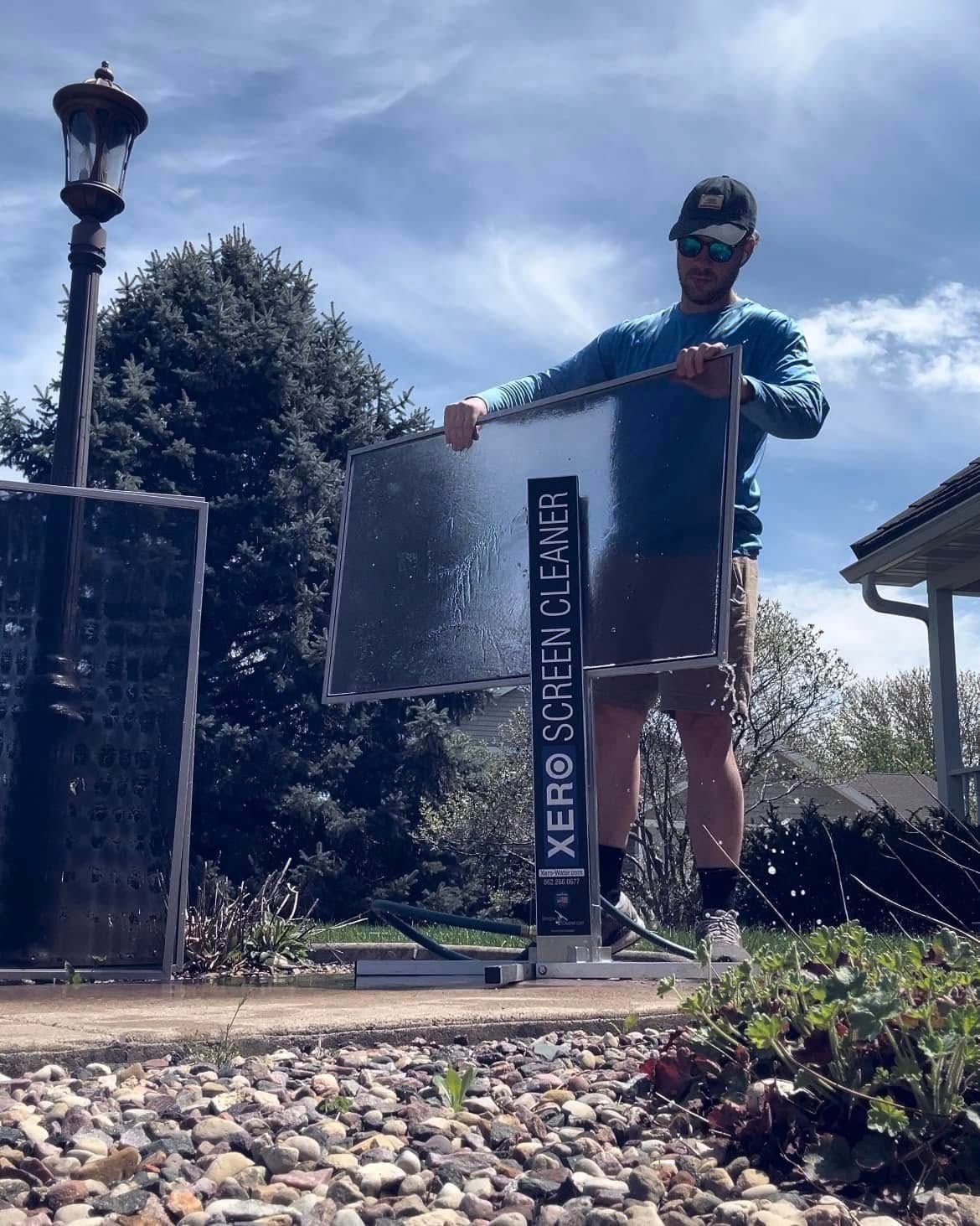 Man spraying water on two reflective panels outdoors.