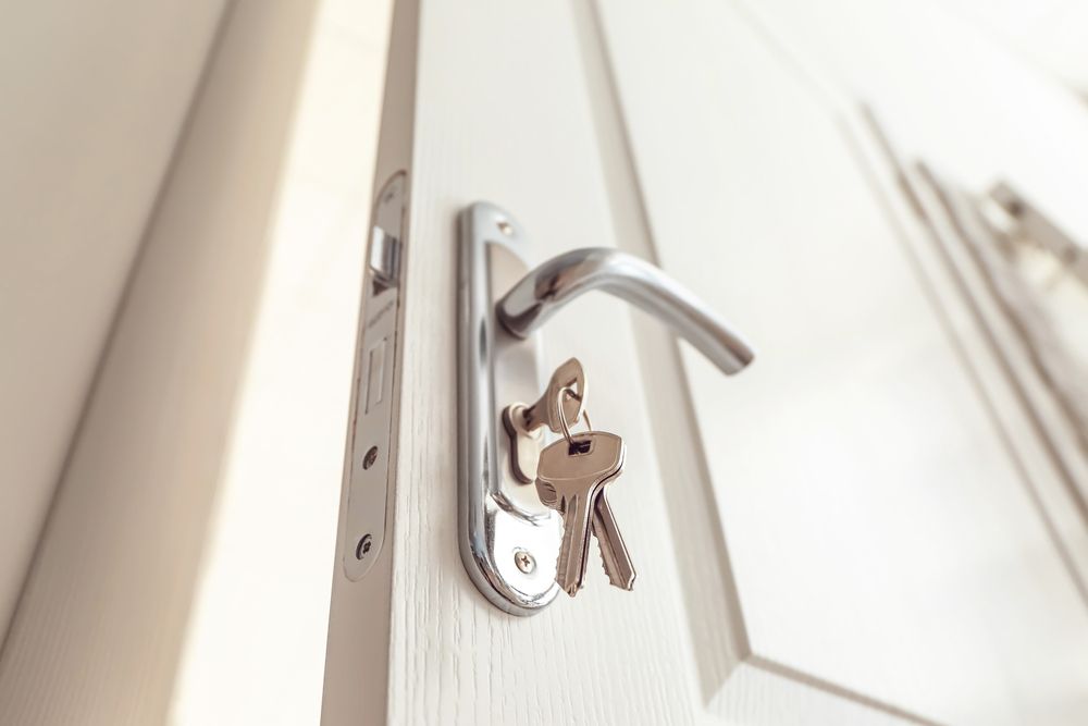 Keys Hanging on a Silver Door Handle on a White Door — Cairns Locksmiths in Freshwater, QLD