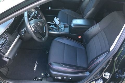 Black car interior with leather seats, steering wheel, and floor mats.