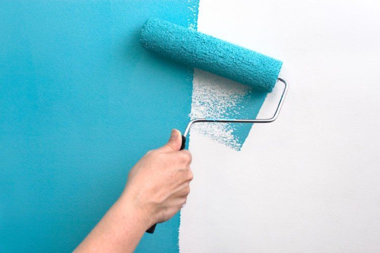 A person is painting a wall blue and white with a paint roller.
