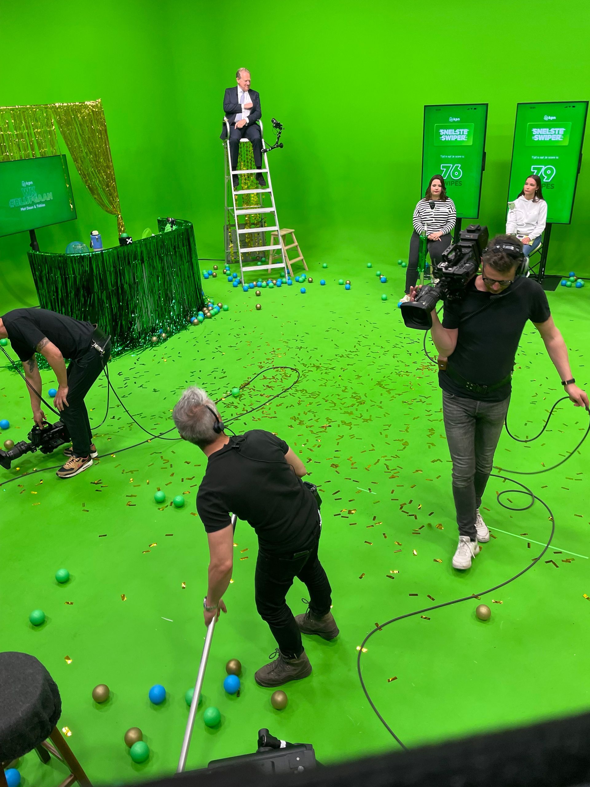 Een groep mensen staat voor een groen scherm.