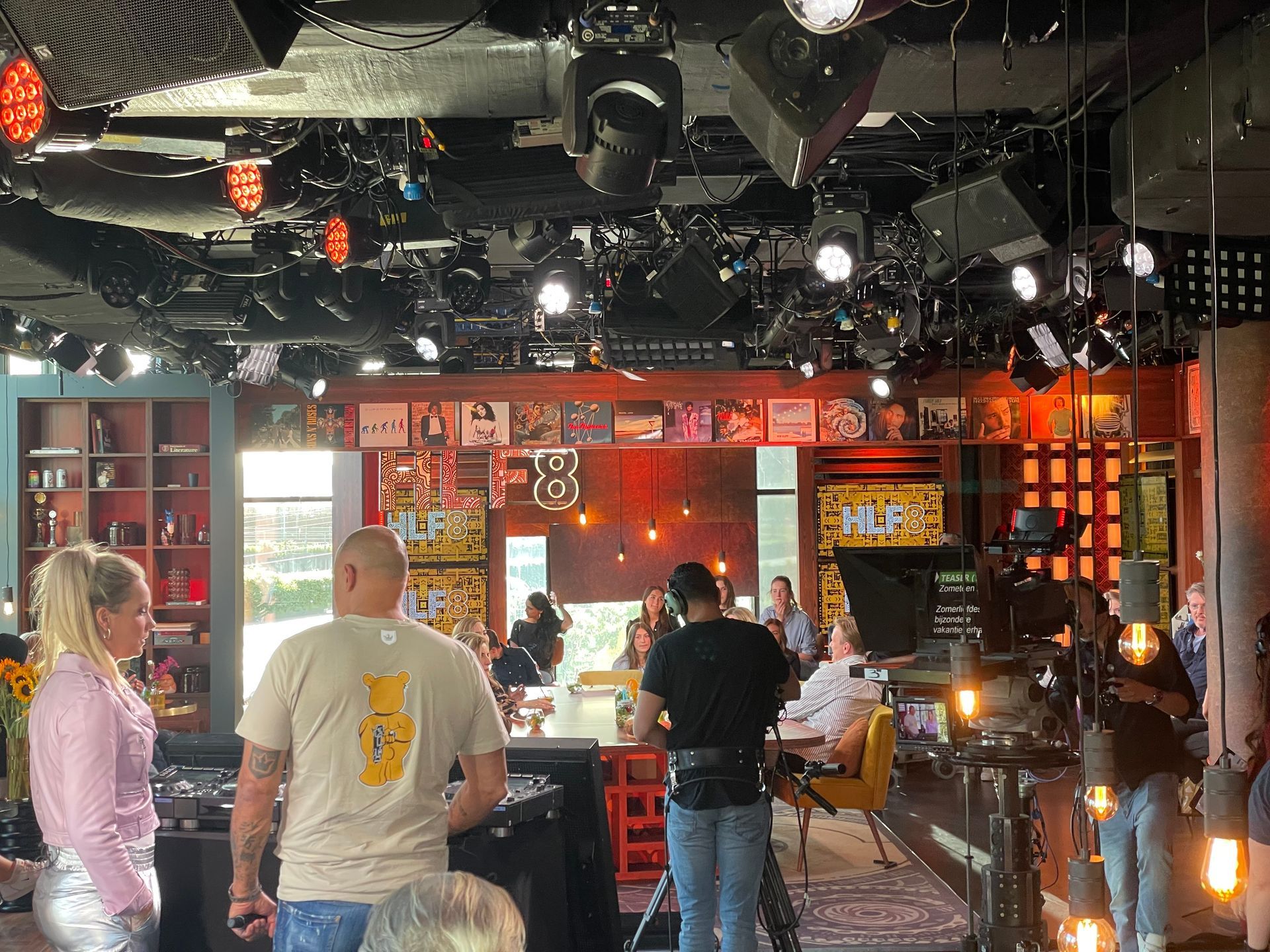 Een groep mensen staat in een kamer met veel lampen aan het plafond.