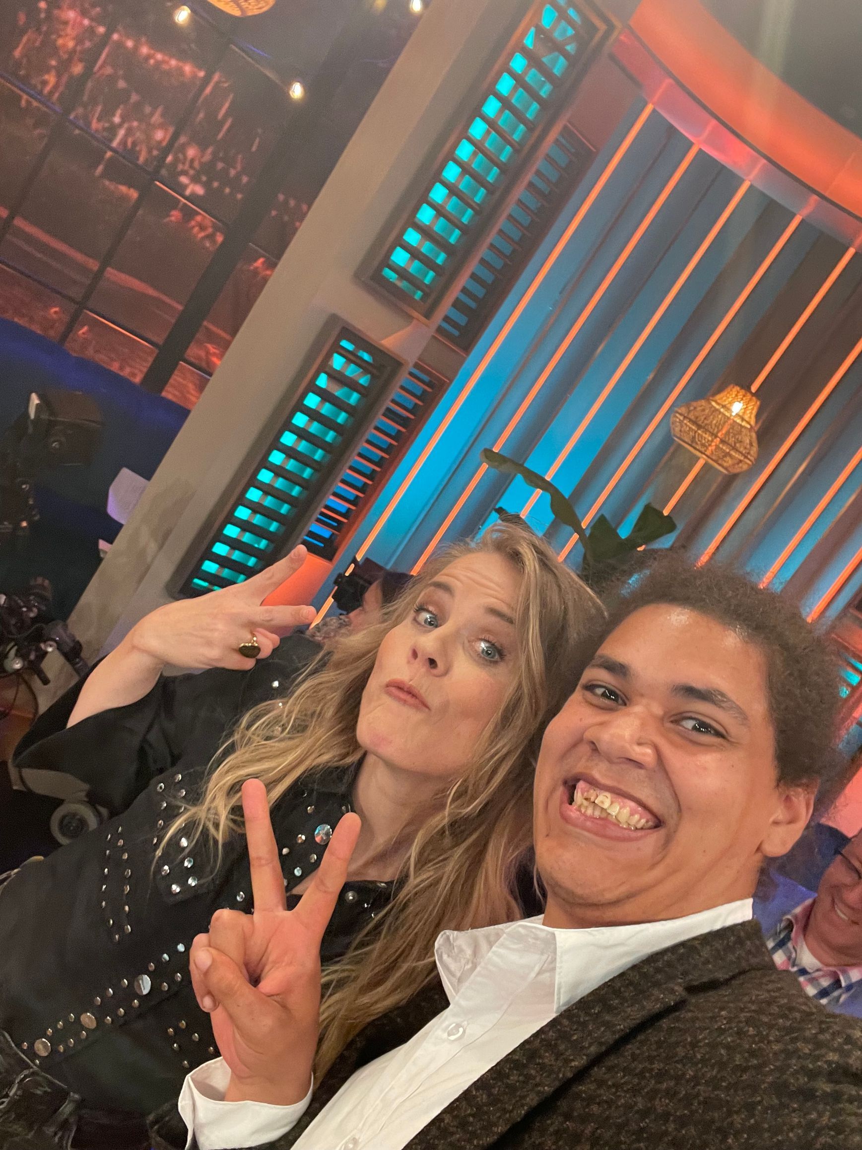 Een man en een vrouw poseren voor een foto en de man maakt een vredesgebaar.