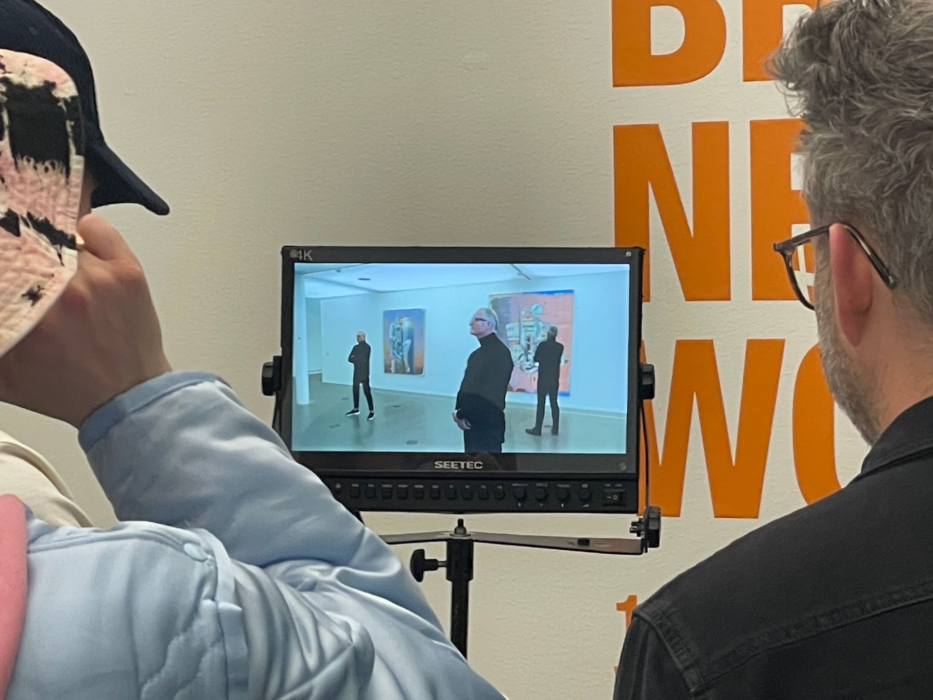 Een man met een hoed kijkt naar een video op een Sony-monitor