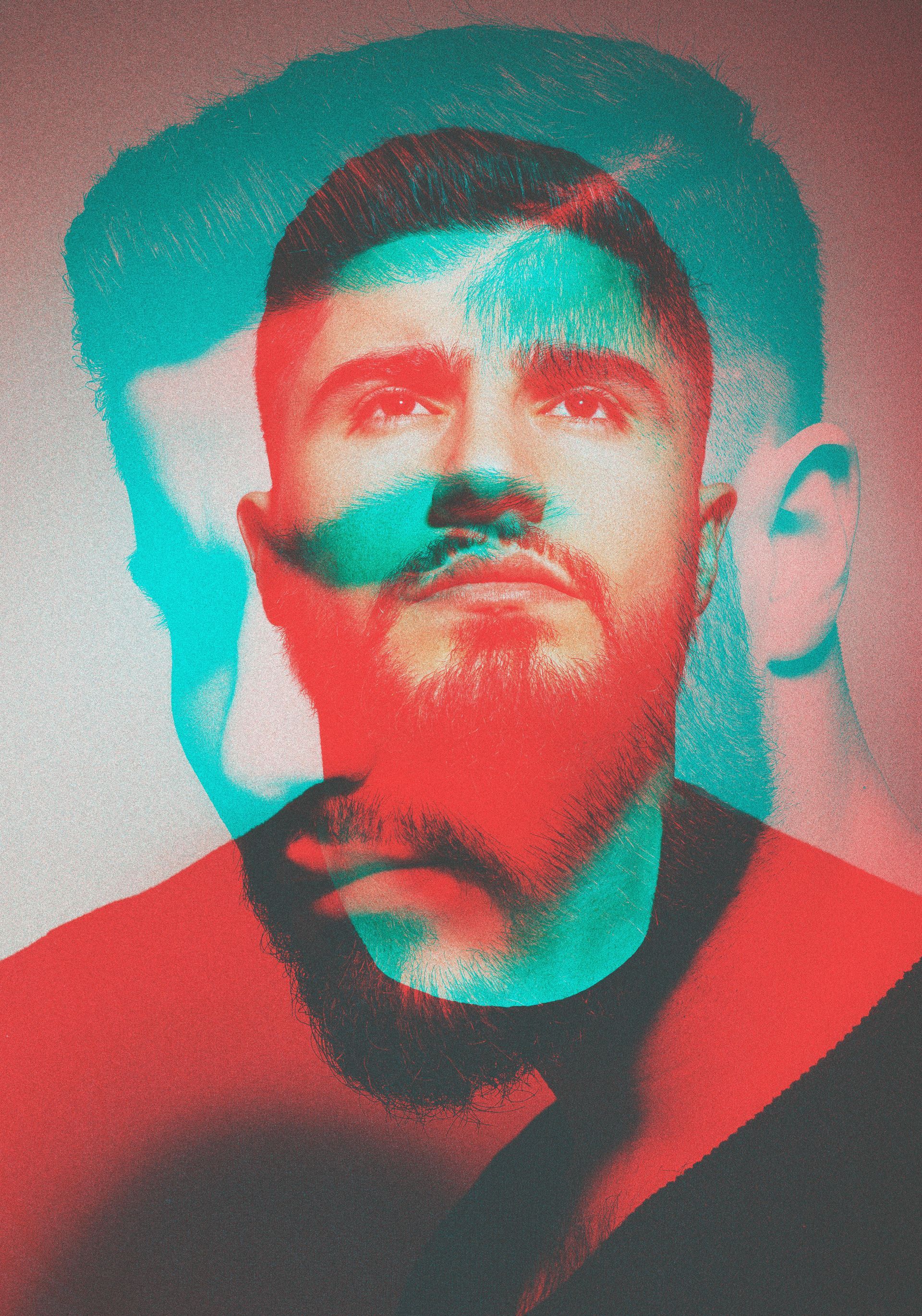 Een man met een baard draagt een rood en blauw overhemd en een stropdas.