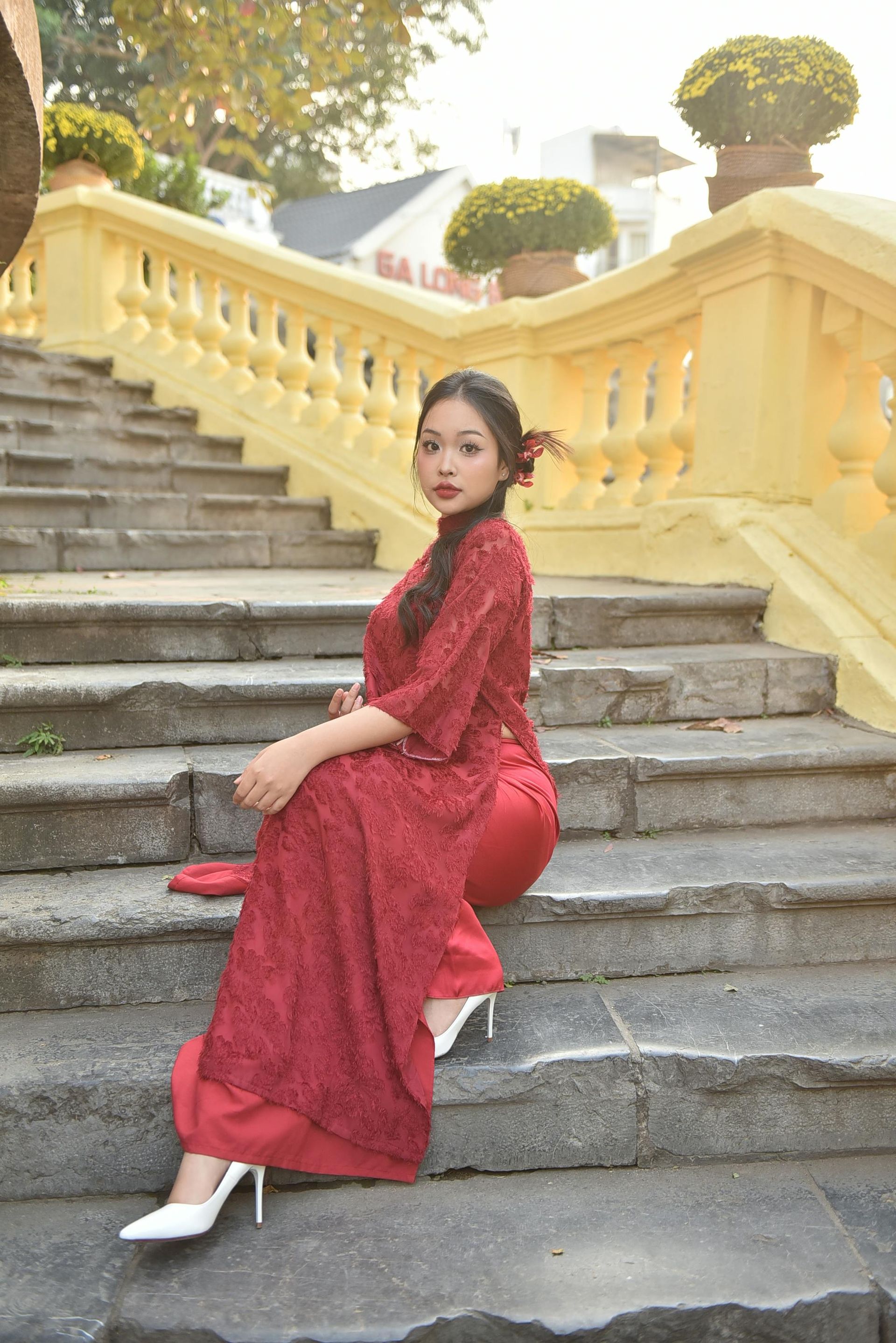 Een vrouw in een rode jurk zit op een trap.