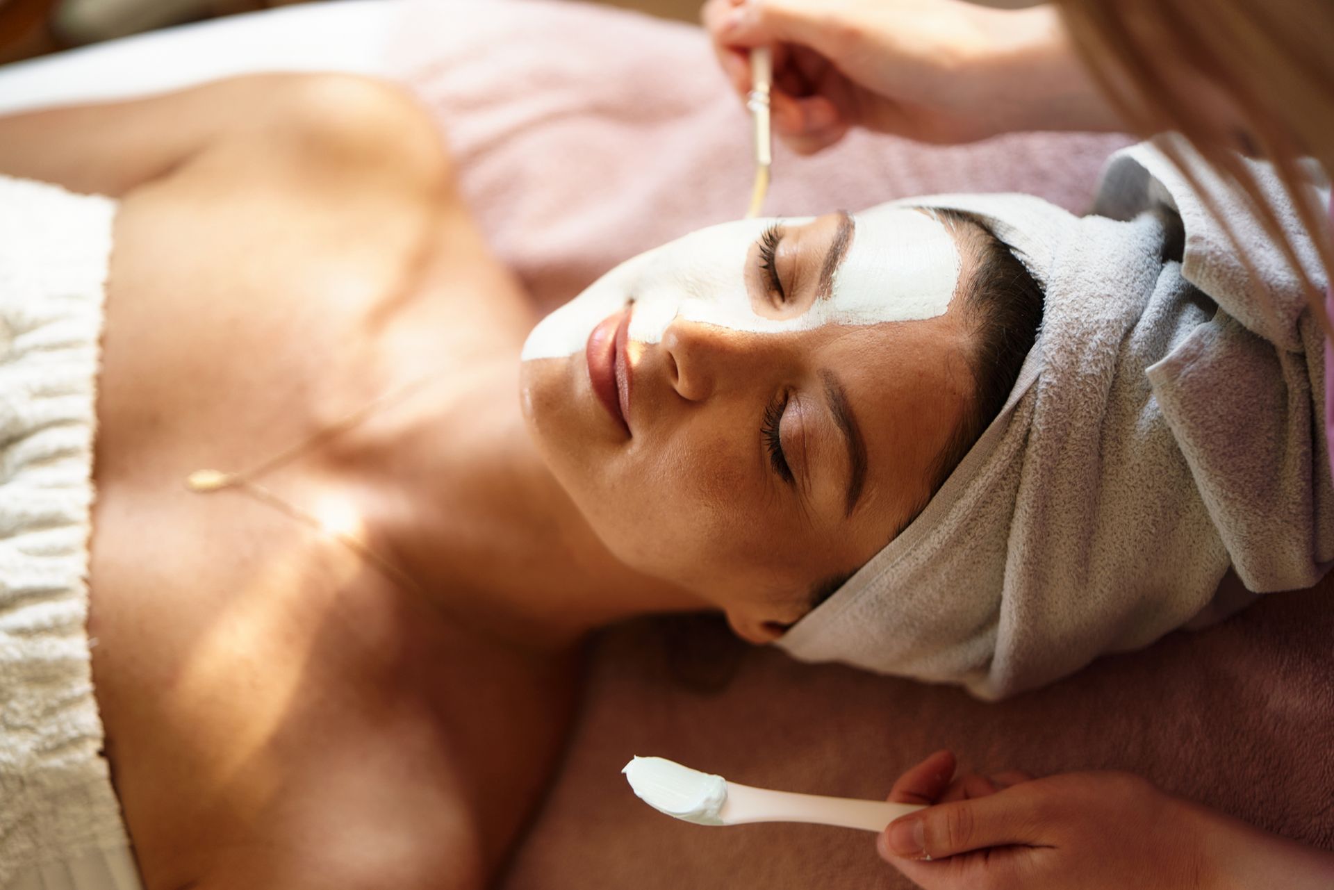 Woman receiving facial spa treatment with mask, concept of sculptra skin rejuvenation.