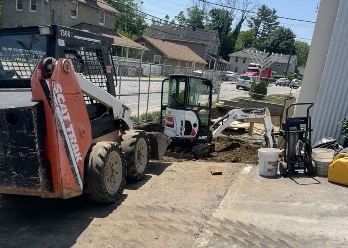 Construction site with skid steer loader, mini excavator, and other tools.