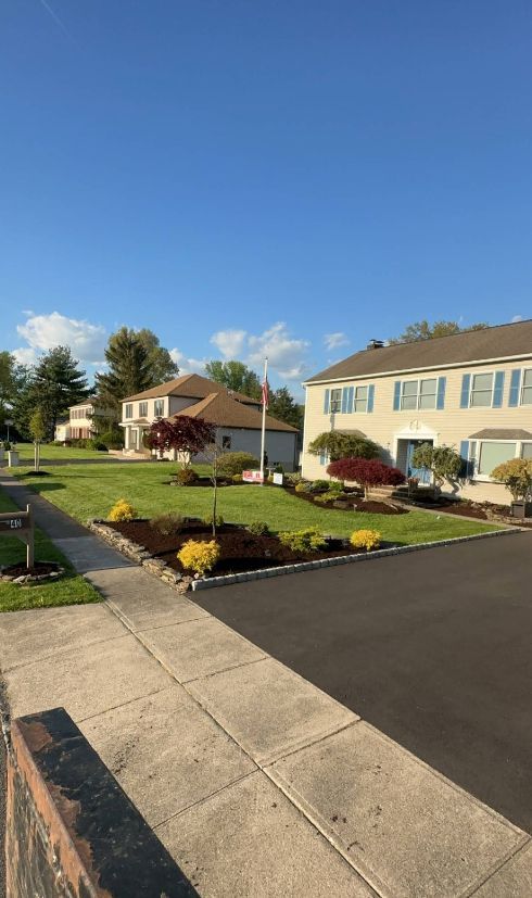 Residential street with houses, green lawns, and blue sky.