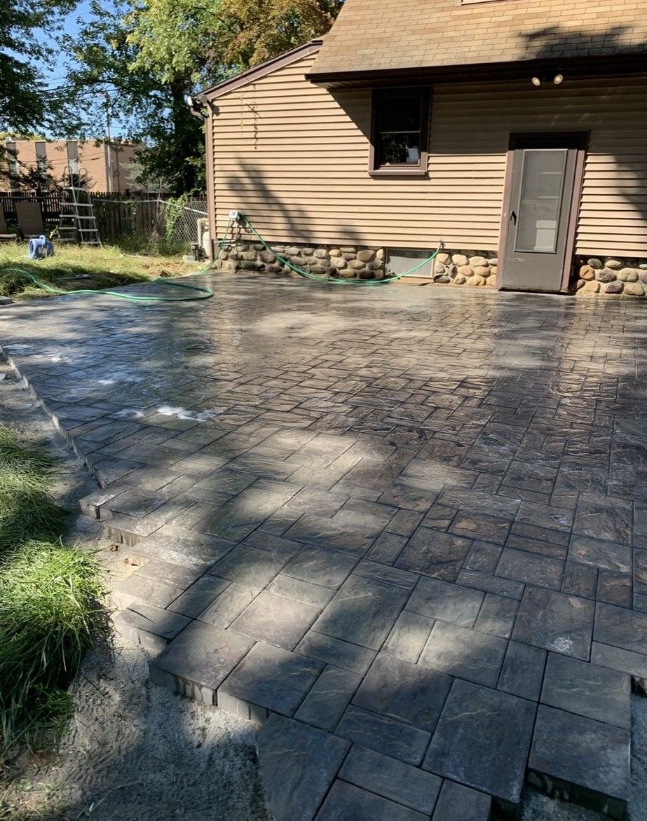 Newly installed gray stone patio next to a house with a door and a window.