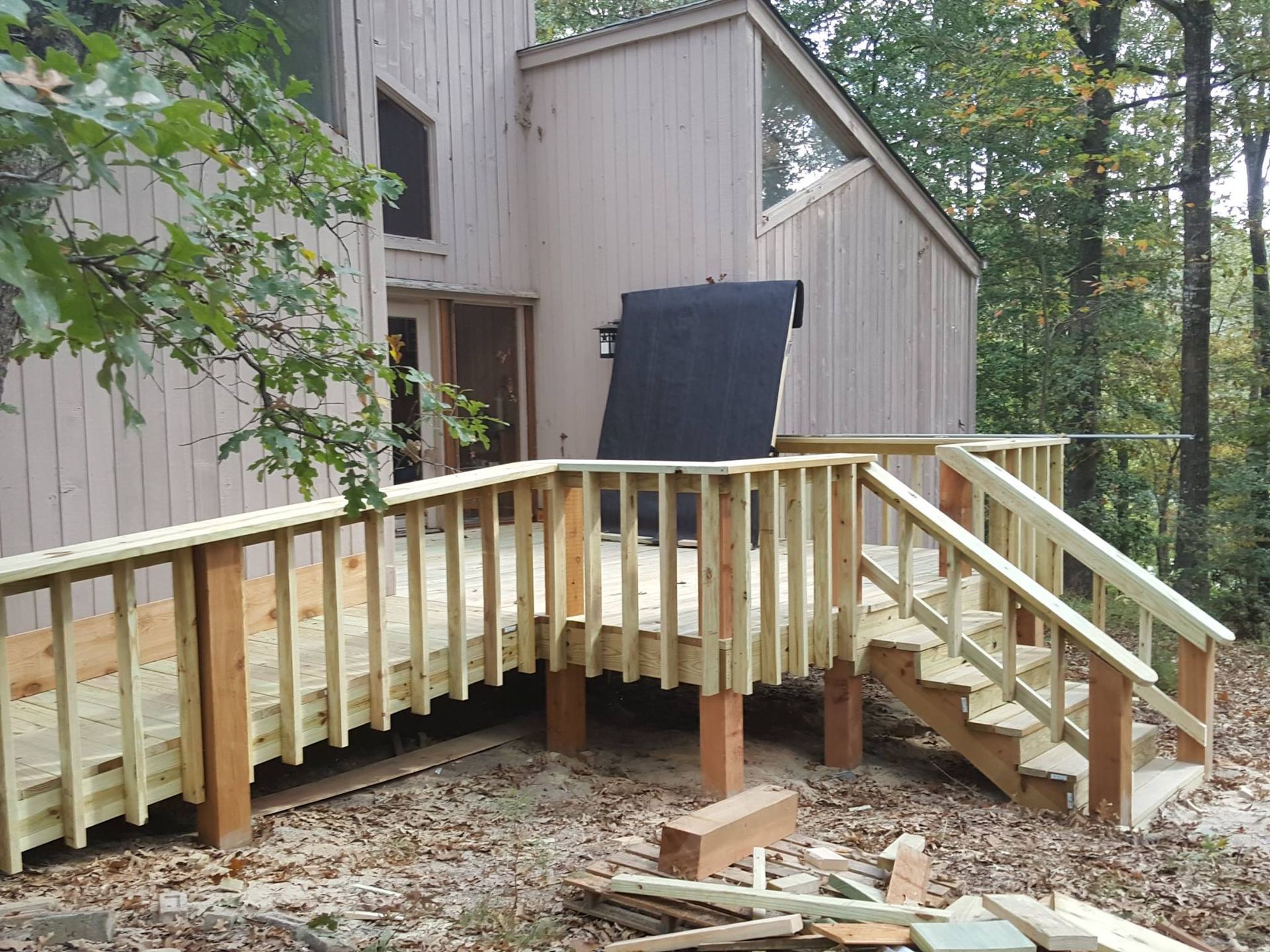 A wooden deck with stairs is being built in front of a house.