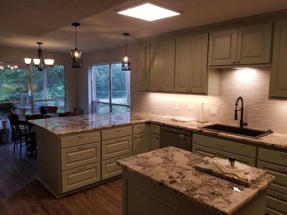 A kitchen with green cabinets and granite counter tops.