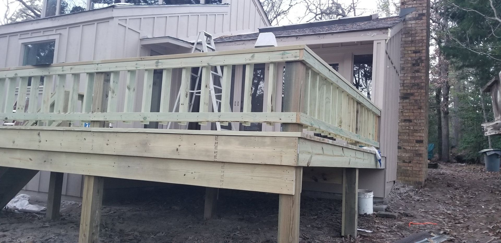 A wooden deck is sitting in front of a house.