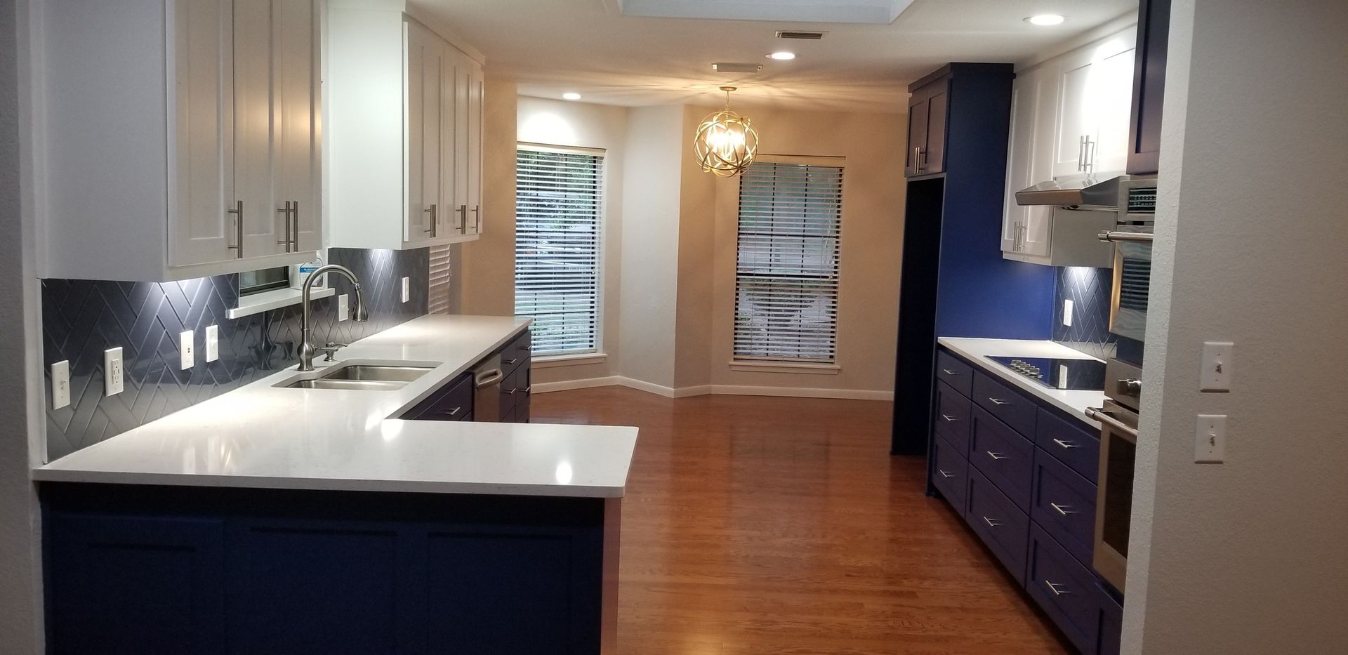 A kitchen with blue cabinets , white counter tops , and stainless steel appliances.