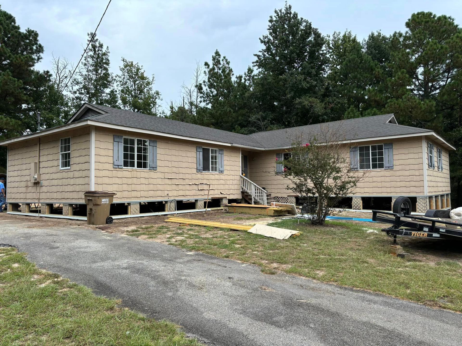 A house is being built on stilts and a trailer is parked in front of it.