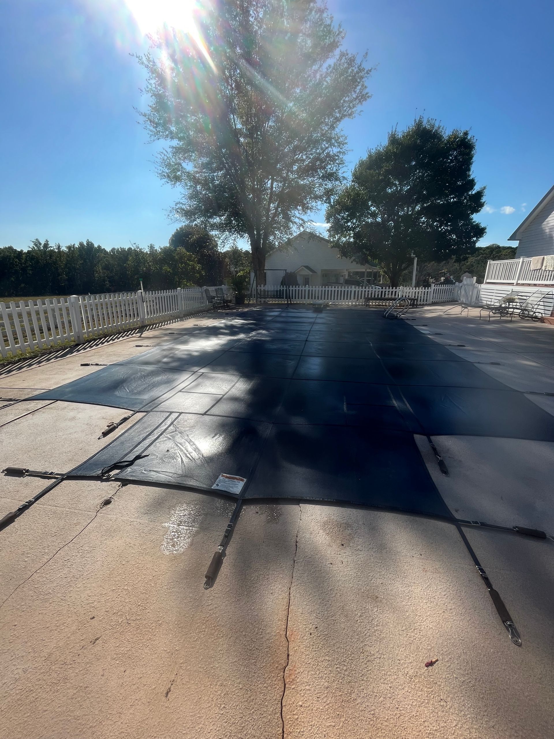 A concrete driveway with a tree in the background and a house in the background.