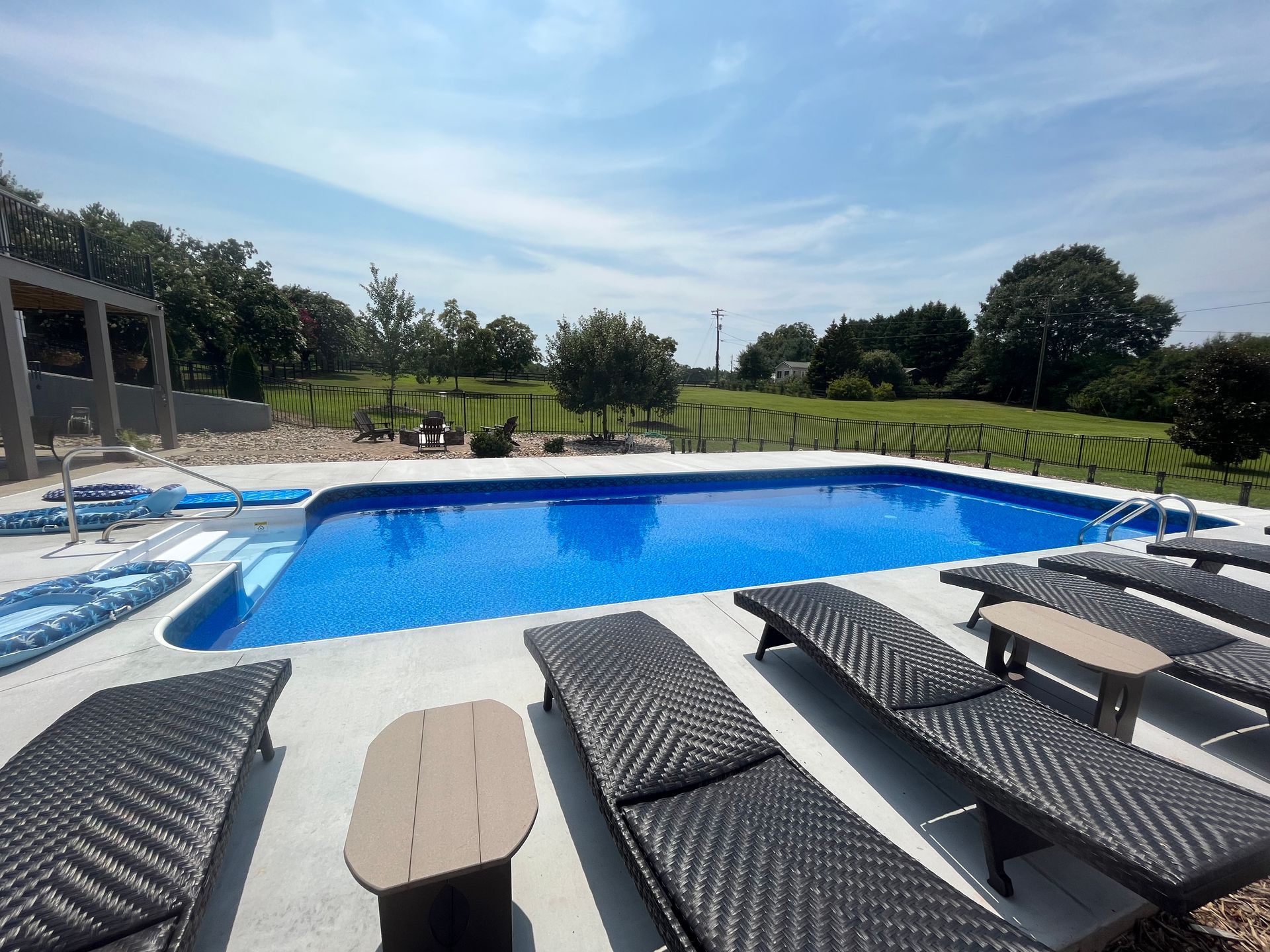 A large swimming pool surrounded by lounge chairs and a table