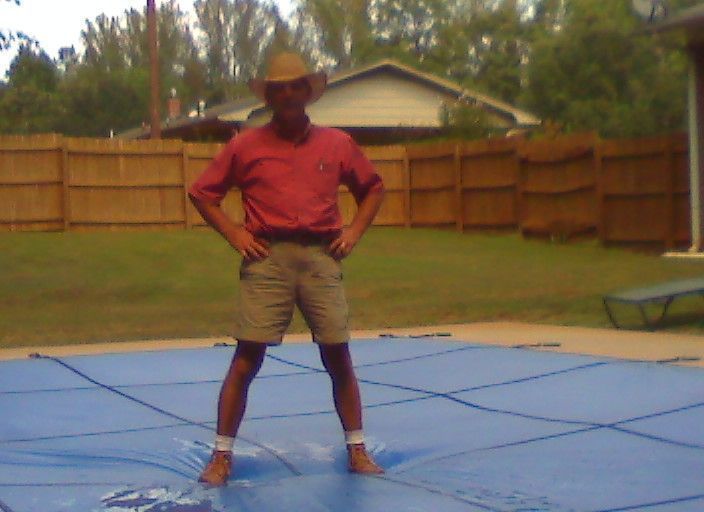 A man in a cowboy hat is standing on a blue mat