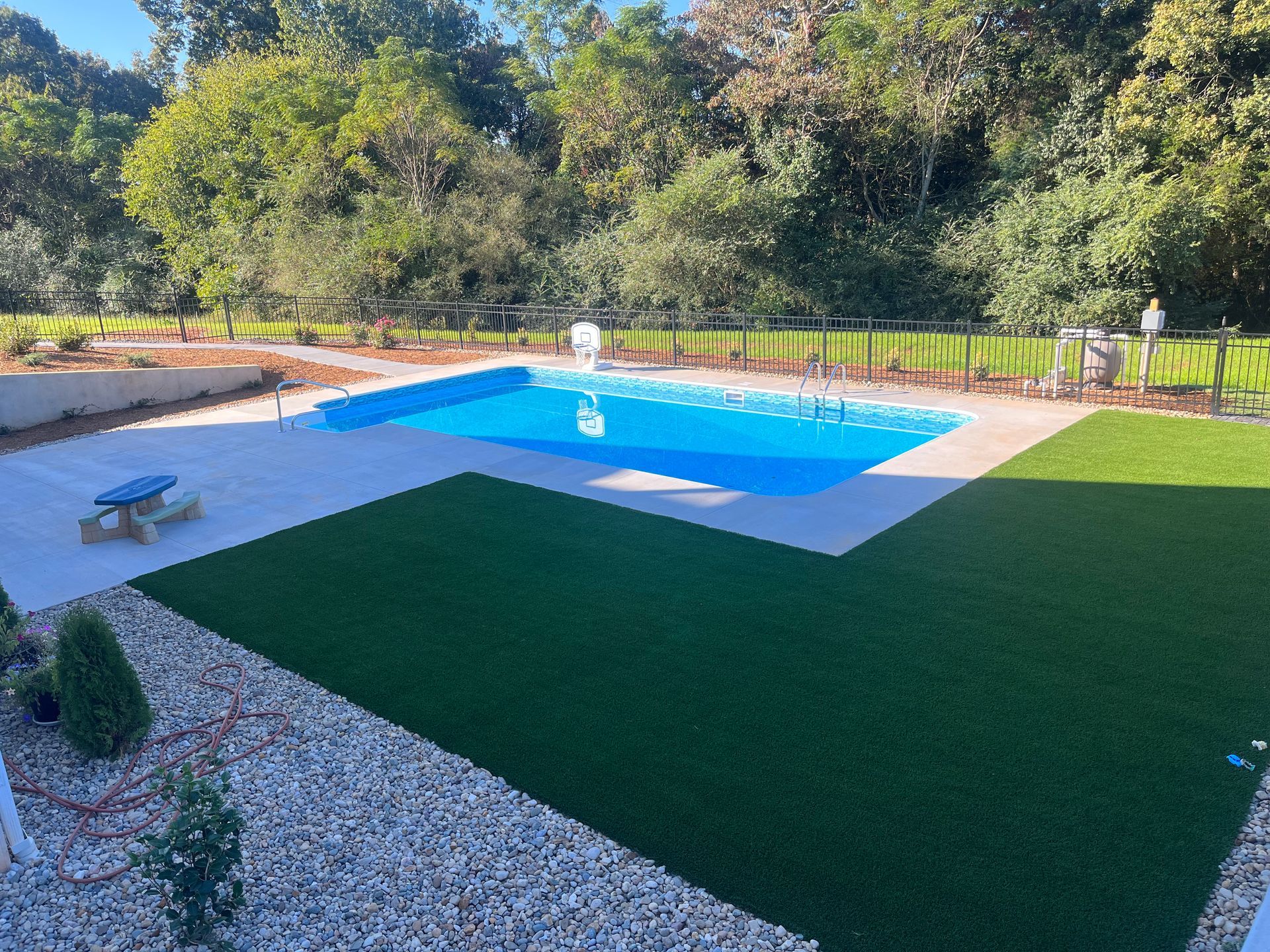A large swimming pool is surrounded by a lush green lawn.