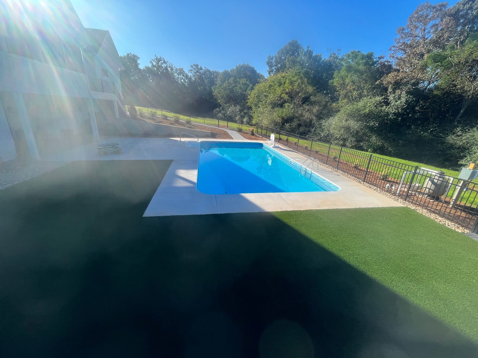 There is a large swimming pool in the backyard of a house.