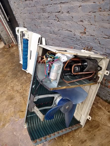 Aire acondicionado desmontado que muestra sus componentes interiores: compresor, ventilador y serpentines. 