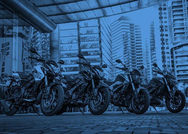 Fileira de motocicletas estacionadas em uma rua da cidade, com a iluminação azulada sob uma passarela coberta.