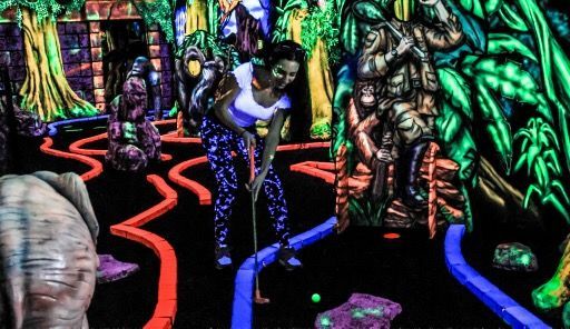 A group of people are playing glow in the dark mini golf.