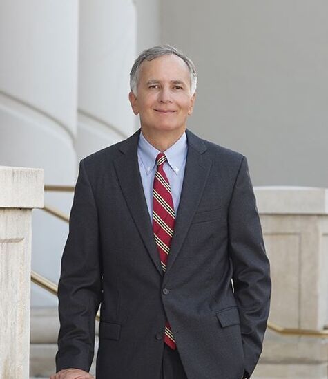 A man in a suit and tie is standing with his hands in his pockets