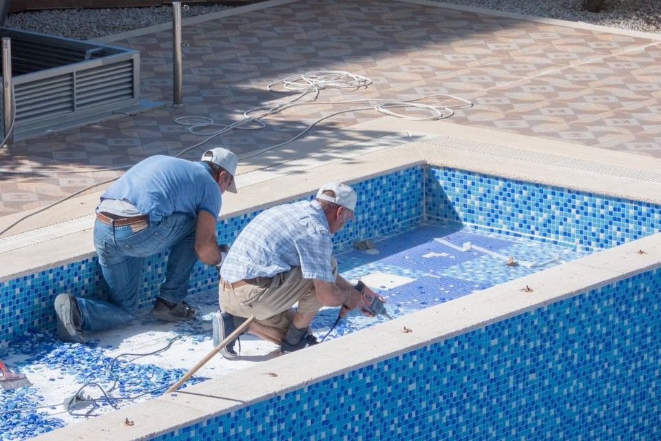 An image of workers repairing and replacing pool tile.
