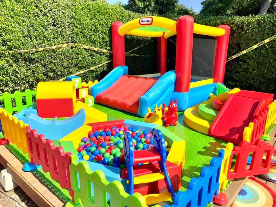 A colorful playground with a bouncy house , slide , and ball pit.