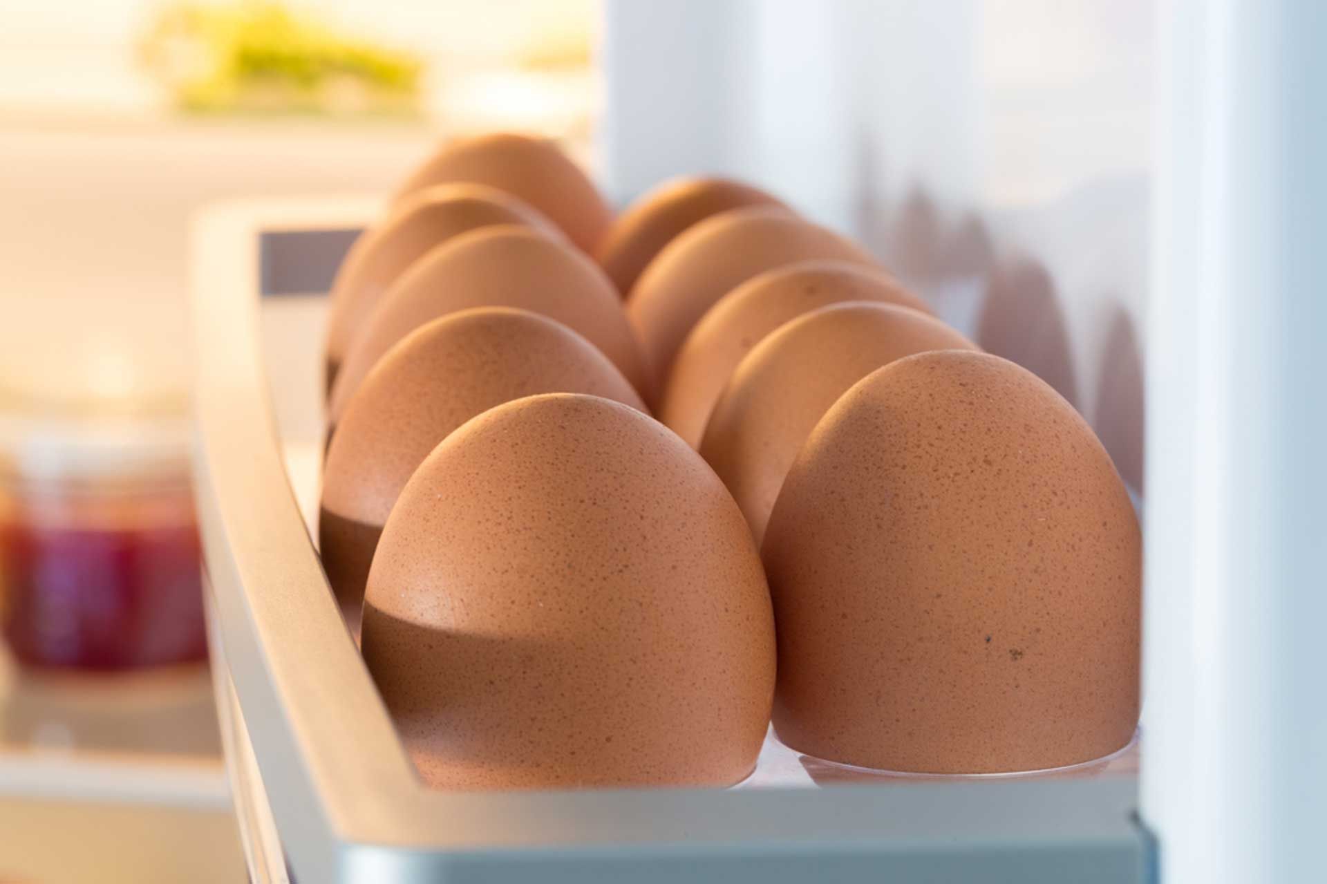 Los huevos están en un estante en un refrigerador.