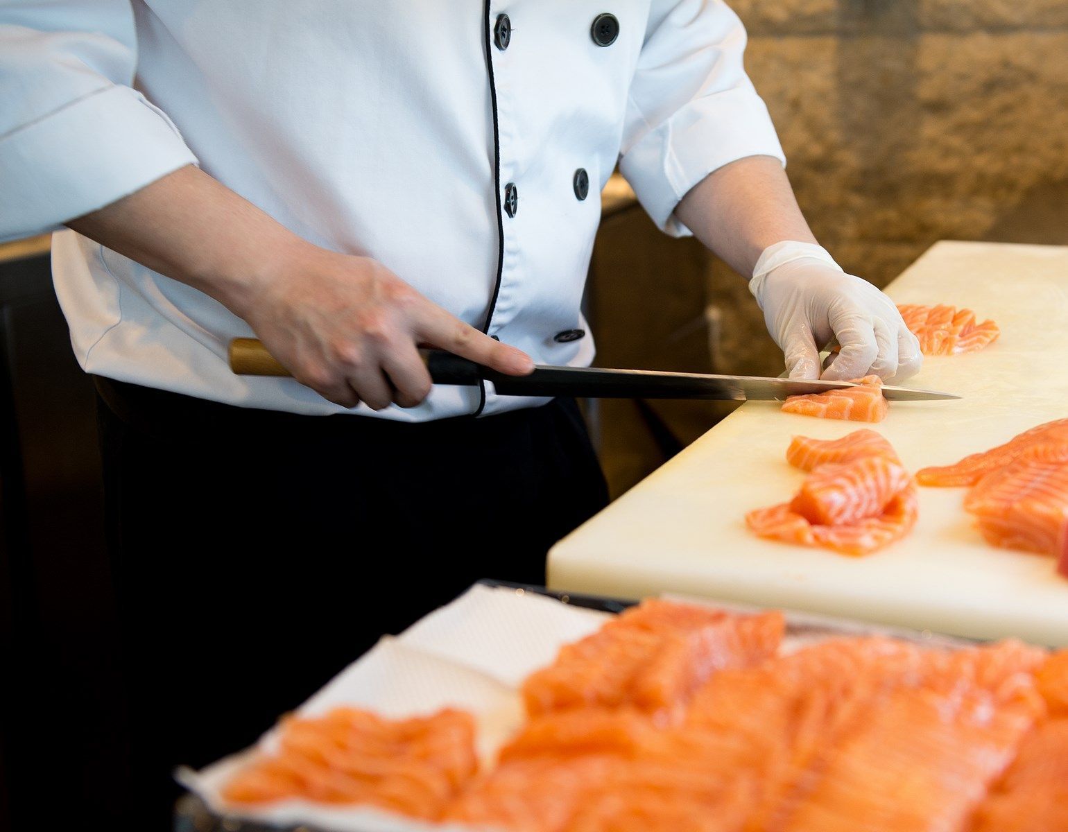 Un chef está cortando salmón en una tabla de cortar.