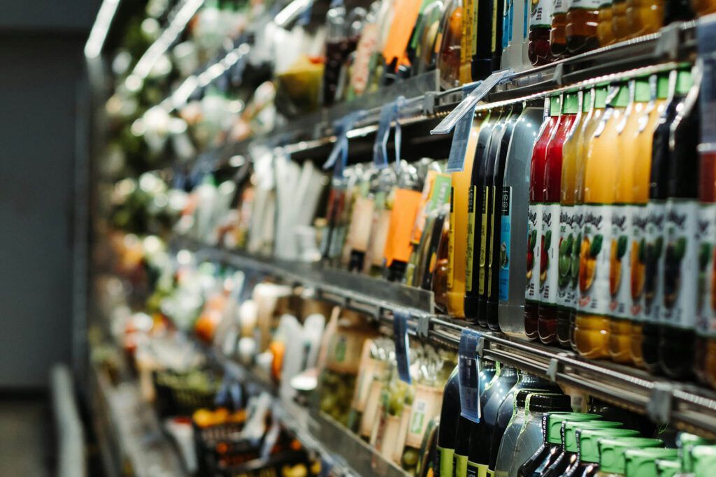 Una fila de estantes en una tienda de comestibles llenos de botellas de jugo.