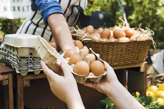 Una persona le está entregando una caja de huevos a otra persona.