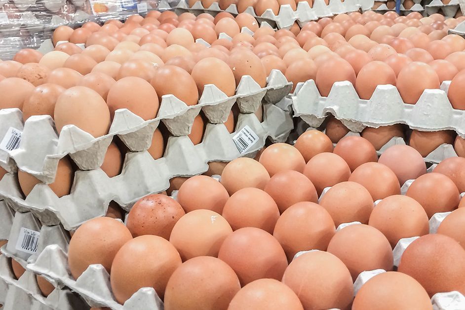 Un montón de huevos se apilan uno encima del otro en bandejas de cartón.