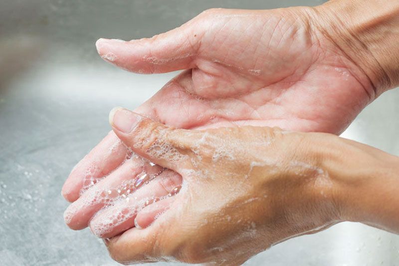Una persona se lava las manos en un lavabo con agua y jabón.