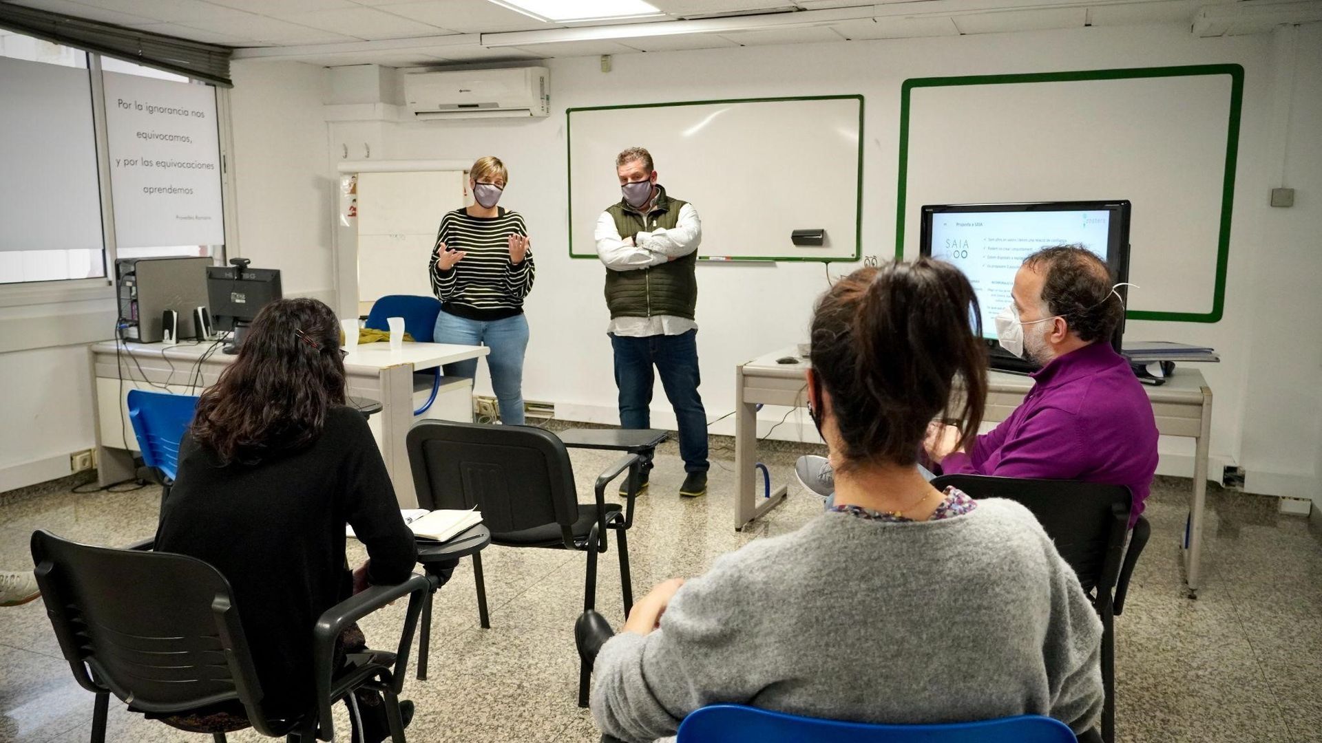 Un grupo de personas están sentadas en un aula con máscaras.