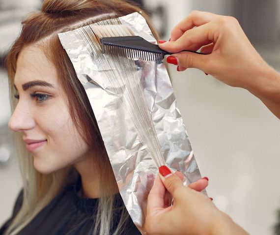 A woman is getting her hair dyed in a salon.