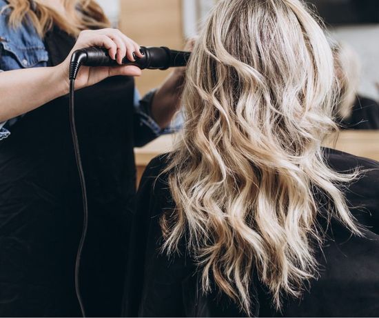 A woman is getting her hair blow dried by a hairdresser.