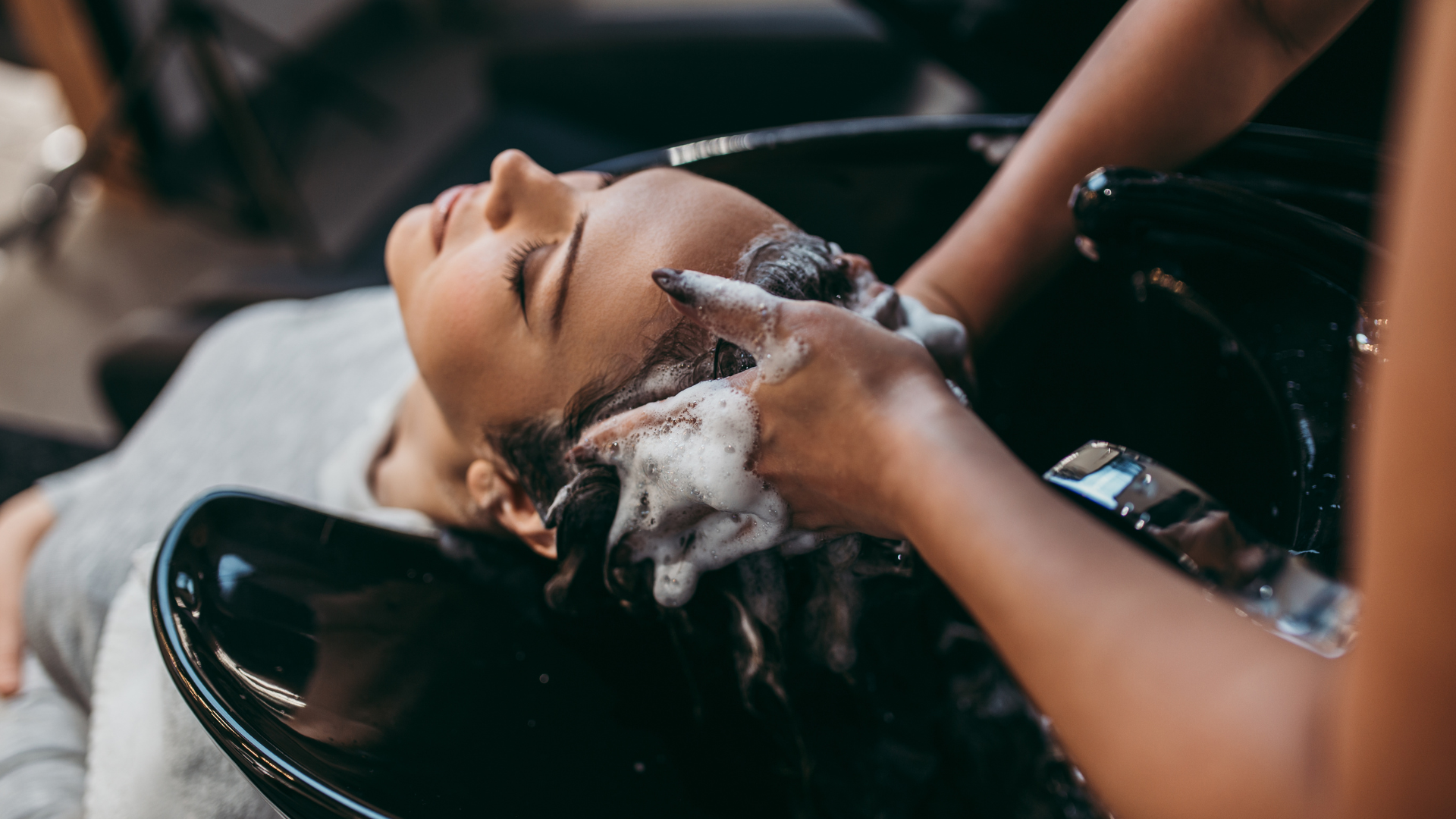 A woman is getting her hair washed at a salon.