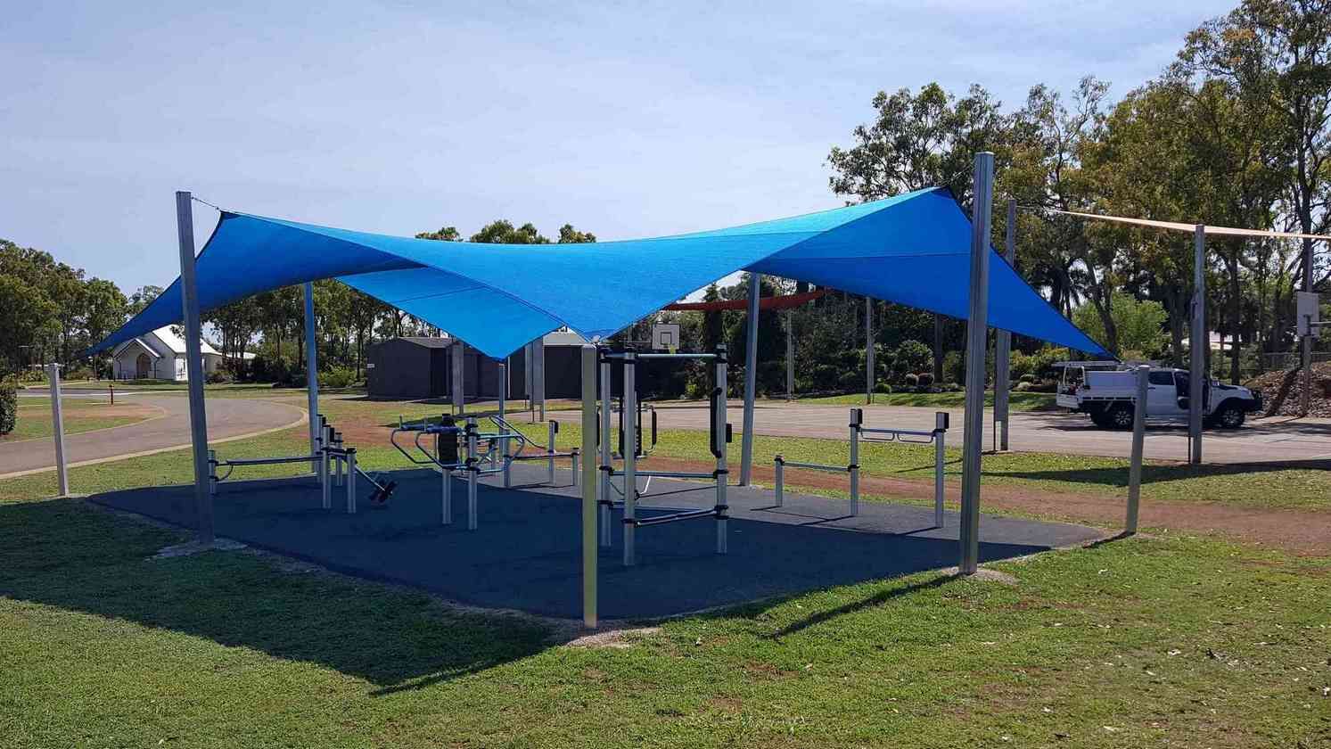 A Blue Umbrella Is Covering A Playground In A Park — Style Shades Installation In Edmonton, QLD