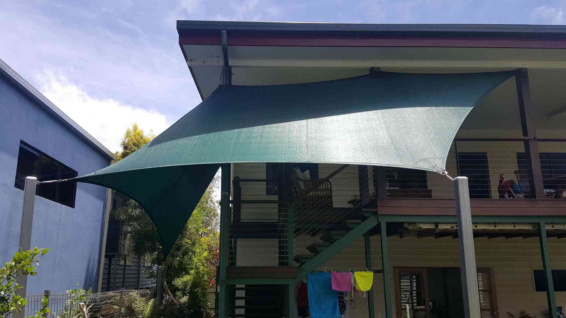 A Large Green Umbrella Is Sitting In Front Of A House — Style Shades Installation In Edmonton, QLD