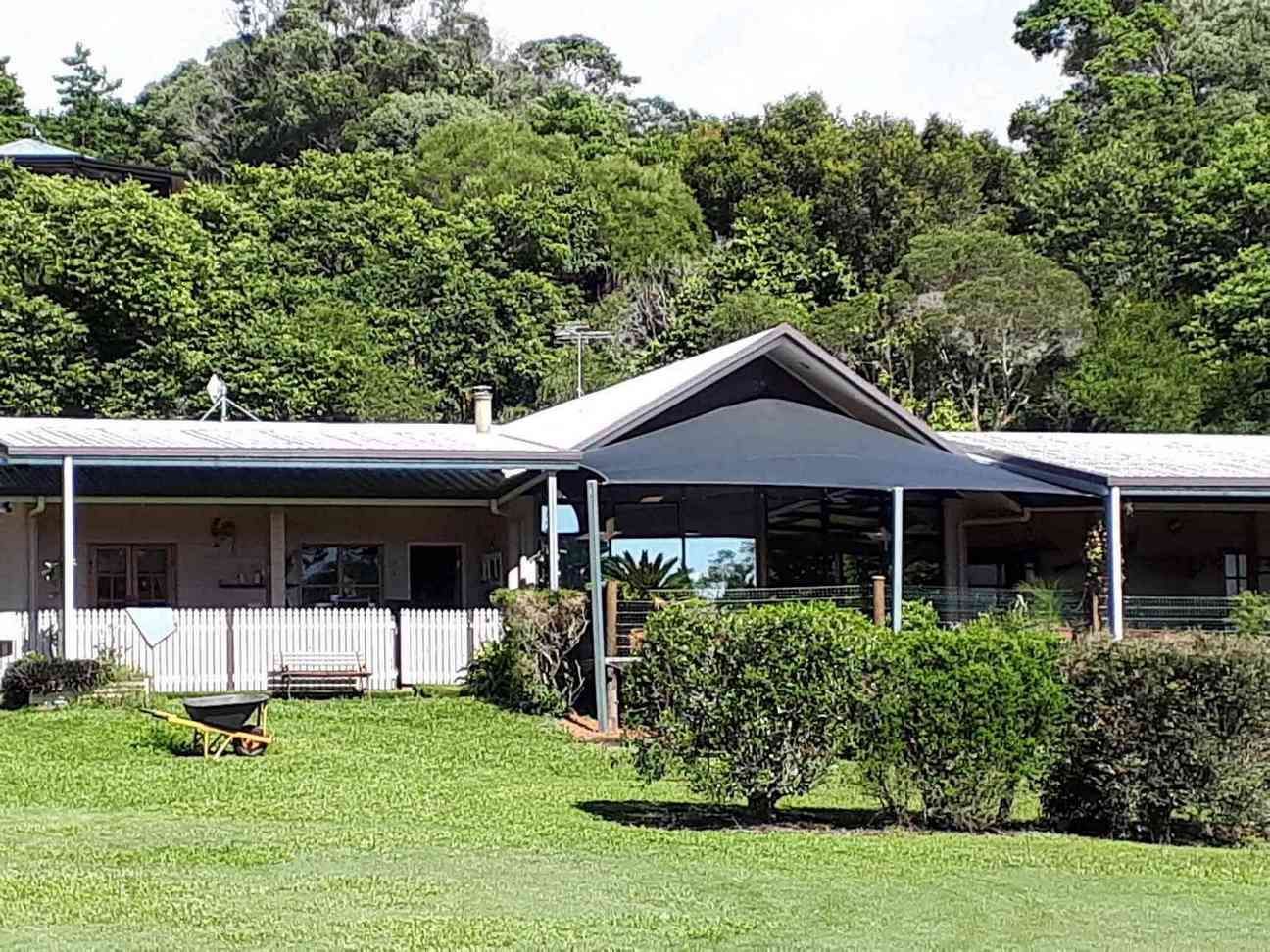 A Large House With A Large Lawn In Front Of It Surrounded By Trees — Style Shades Installation In Edmonton, QLD