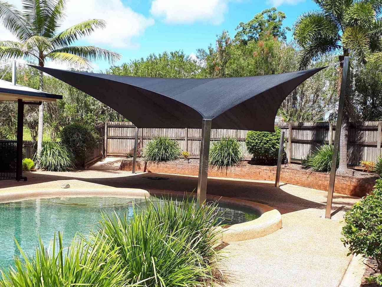 A Large Black Umbrella Is Sitting Next To A Swimming Pool — Style Shades Installation In Atherton Tablelands, QLD