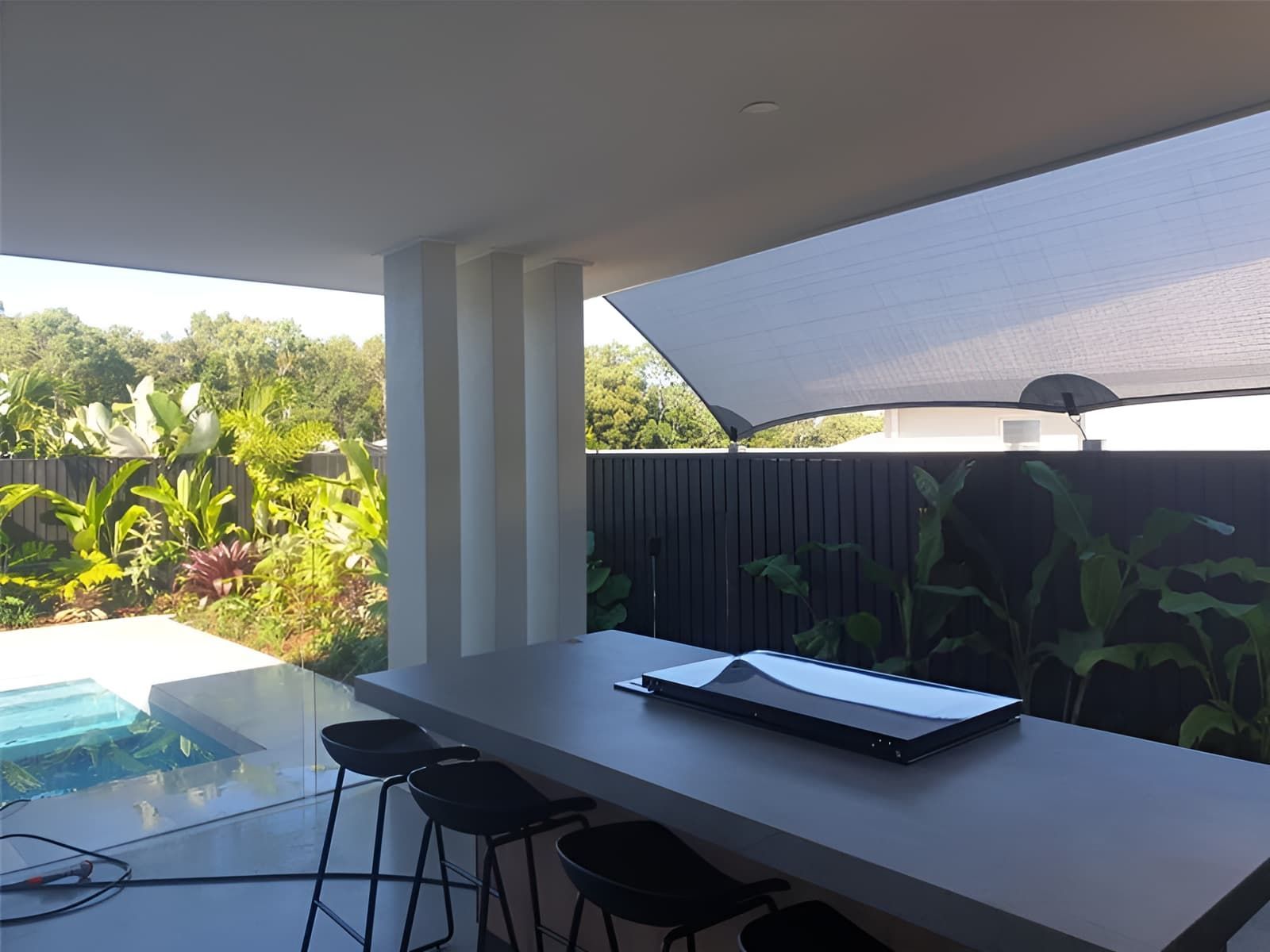 A Patio With A Table And Stools And An Umbrella Over It — Style Shades Installation In Edmonton, QLD