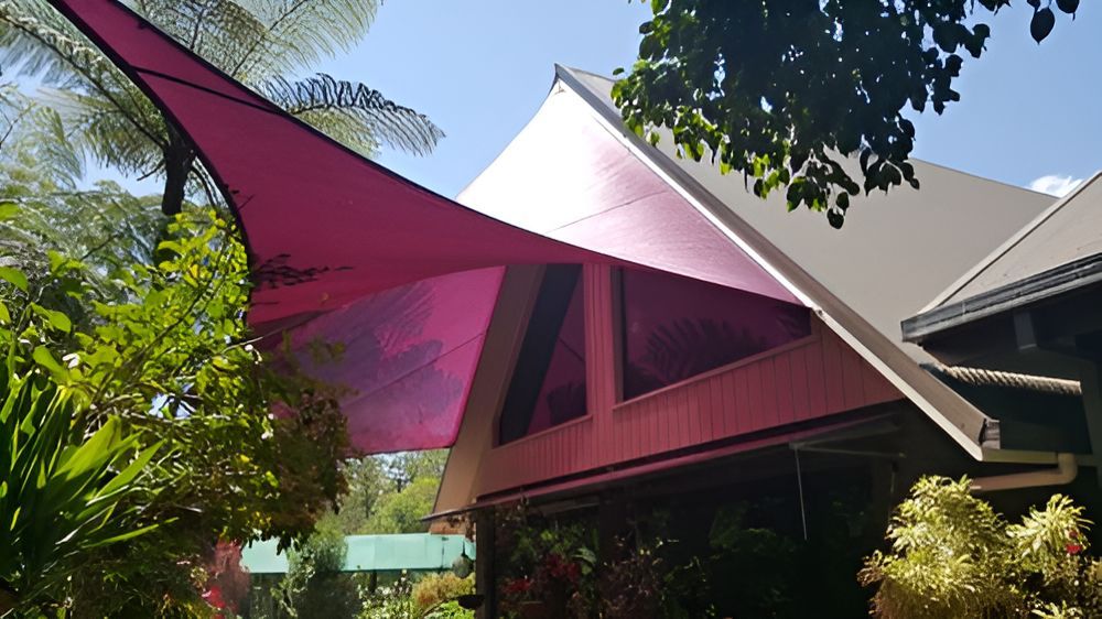 A Pink Umbrella Is Hanging From The Roof Of A House — Style Shades Installation In Edmonton, QLD