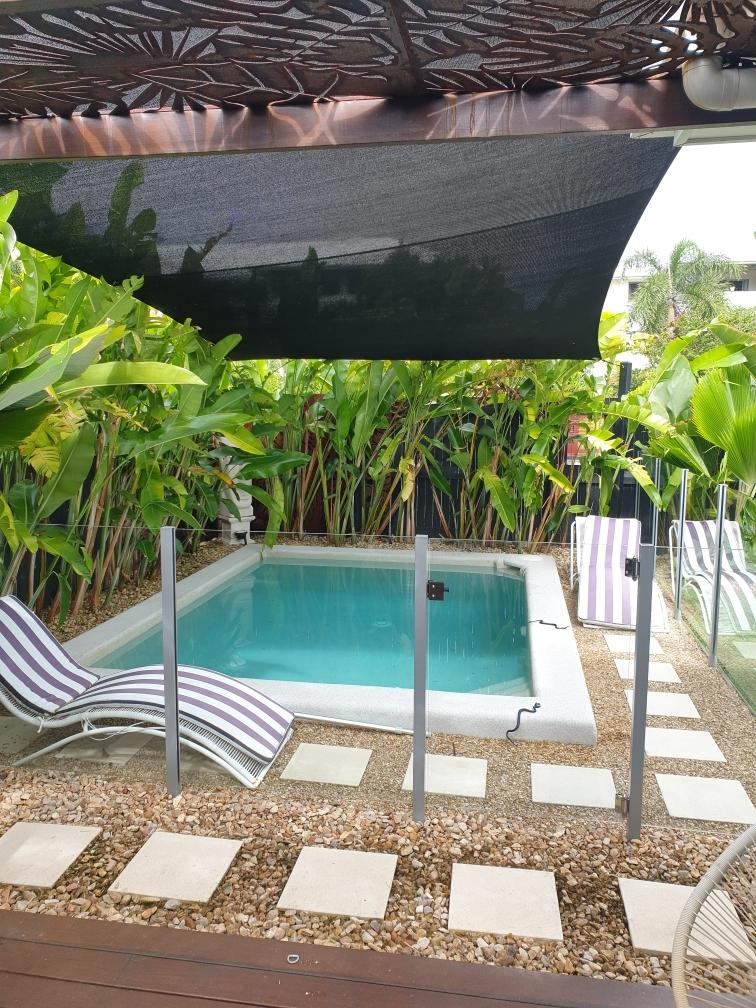 A Small Swimming Pool With A Black Umbrella Over It — Style Shades Installation In Edmonton, QLD